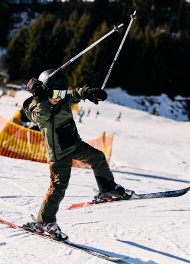 Ein Kind beim Skifahren im Winter auf einer Skipiste, trägt Helm, Skibrille und Winterkleidung. | ©  Kleinwalsertal Tourismus eGen • Fotograf: Oliver Farys