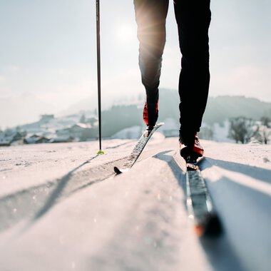 Skifahrer auf der Schwarz-Wasserloipe im Kleinwalsertal, mit Fokus auf die Skier und den unteren Körper, bei sonnigem Winterwetter. | © Kleinwalsertal Tourismus eGen • Fotograf: Oliver Farys