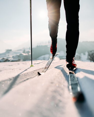 Skifahrer auf der Schwarz-Wasserloipe im Kleinwalsertal, mit Fokus auf die Skier und den unteren Körper, bei sonnigem Winterwetter. | © Kleinwalsertal Tourismus eGen • Fotograf: Oliver Farys