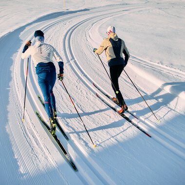 Zwei Skifahrer im klassischen Skilanglauf auf einer schneebedeckten Loipe im Kleinwalsertal, Schwarzwasserloipe, während der Winter-2025-Saison. | © Kleinwalsertal Tourismus eGen • Fotograf: Oliver Farys