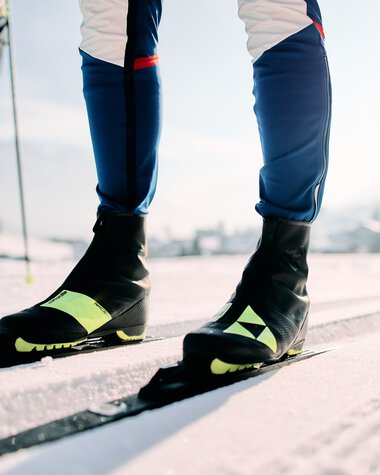 Skifahrer im klassischen Langlauf auf der Schwarzwasserloipe im Kleinwalsertal, Fokus auf die Skischuhe und die Schneeloipe. | © Kleinwalsertal Tourismus eGen • Fotograf: Oliver Farys
