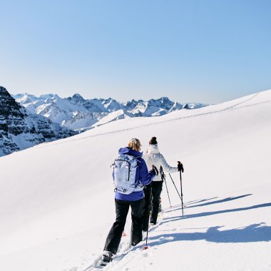 Drei Personen beim Schneeschuhwandern in der verschneiten Berglandschaft des Kleinwalsertals. | © Kleinwalsertal Tourismus eGen • Fotograf: Oliver Farys