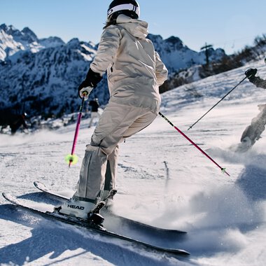 Zwei Skifahrer unterwegs auf der Piste am Kanzelwand mit Bergpanorama im Hintergrund. | © Kleinwalsertal Tourismus eGen • Fotograf: Oliver Farys