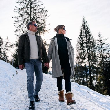 Ein Mann und eine Frau wandern im Schnee in einem winterlichen Wald. Es ist eine Winterwanderung im Kleinwalsertal. | © Kleinwalsertal Tourismus eGen • Fotograf: Oliver Farys