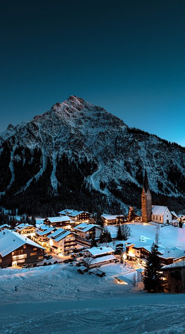 Winter mountain landscape with snow-covered villages and mountains under a clear, dark sky. | © Kleinwalsertal Tourismus eGen • Photographer: Robert Niederwolfsgruber