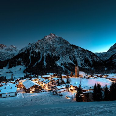 Winter mountain landscape with snow-covered villages and mountains under a clear, dark sky. | © Kleinwalsertal Tourismus eGen • Photographer: Robert Niederwolfsgruber