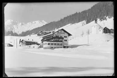 Schneebedecktes Sporthotel Walsertal in Baad mit umgebenden Bergen und traditionellem Gebäude, Aufnahme in Schwarzweiß. | © Kleinwalsertal Tourismus eGen • Karl Marx Kessler Archiv