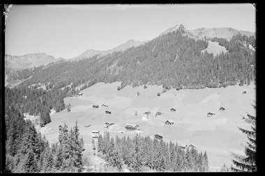 Historisches Schwarz-Weiß-Foto von Baad im Kleinwalsertal, mit Bergen und einzelnen Häusern in der Landschaft. | © Kleinwalsertal Tourismus eGen • Karl Marx Kessler Archiv