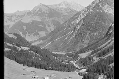 Schöne Berglandschaft im Tal mit kleinen Bauernhöfen, umgeben von hohen Gipfeln, im historischen Schwarz-Weiß-Foto. | © Kleinwalsertal Tourismus eGen • Karl Marx Kessler Archiv