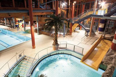Innenansicht des Wonnemar Erlebnisbades in Sonthofen mit Wasserrutschen, einem Wasserbecken und einem Indoor-Badbereich. | © Kleinwalsertal Tourismus eGen • Wonnemar Erlebnisbad Sonthofen