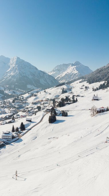 Traumhafter Blick auf das Heuberg-Gebiet mit verschneiten Bergen und Dörfern im Oberstdorf-Kleinwalsertal Gebiet. | © Oberstdorf · Kleinwalsertal Bergbahnen
