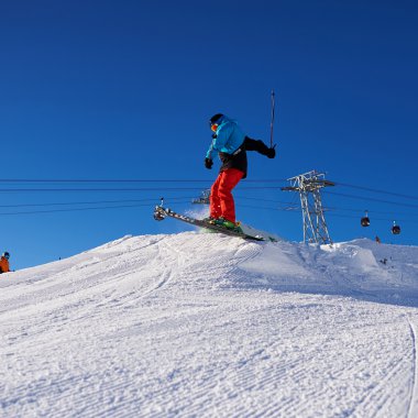 Skifahrer springt beim Skiurlaub in den Bergen im Schnee, blauer Himmel im Hintergrund. | © Kleinwalsertal Tourismus eGen • Oberstdorf Kleinwalsertal Bergbahnen