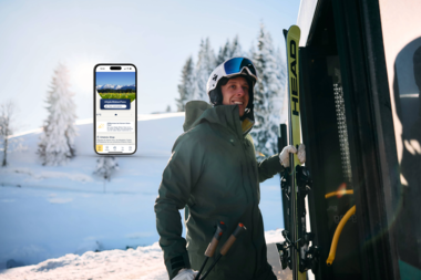 Ein Skifahrer mit Helm und Skiern steht neben einem Fahrzeug im verschneiten Winterland, im Hintergrund Bäume und Berge. | © Kleinwalsertal Tourismus eGen