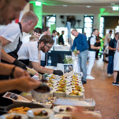 Menschen bedienen sich an einem Buffet bei einem kulinarischen Festival, mit einer Vielzahl an kleinen Speisen und Desserts. | © Kleinwalsertal Tourismus eGen • Fotograf: Isenhoff