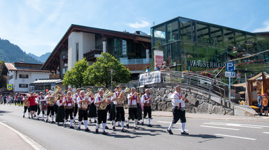 © Kleinwalsertal Tourismus eGen Musikkapelle beim Dorffest in Hirschegg marschiert an der Straße entlang bei sonnigem Wetter. | © Kleinwalsertal Tourismus eGen