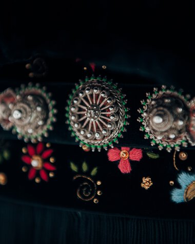 Detailaufnahme eines traditionellen Trachten-Gürtels mit reichlich verzierter Schnalle und floralem Stickmuster. | © Kleinwalsertal Tourismus eGen • Fotograf: Stefan Klauser