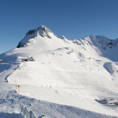 Verschneite Berge in einem Skigebiet mit blauer Himmel, Pisten und Skiliften.