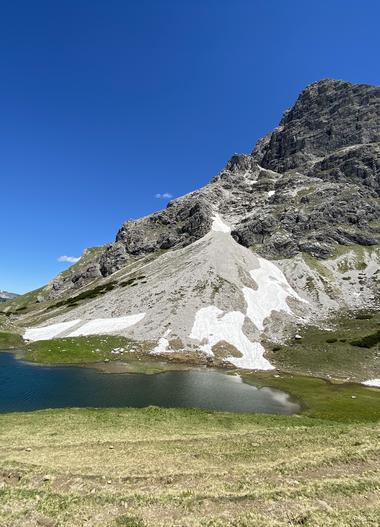 Bergkulisse mit einem kleinen See im Vordergrund und einer großen Bergspitze im Hintergrund, strahlend blauer Himmel. | © Kleinwalsertal Tourismus eGen