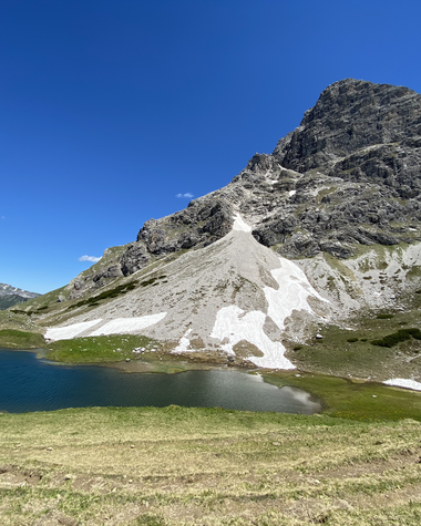 Bergkulisse mit einem kleinen See im Vordergrund und einer großen Bergspitze im Hintergrund, strahlend blauer Himmel. | © Kleinwalsertal Tourismus eGen
