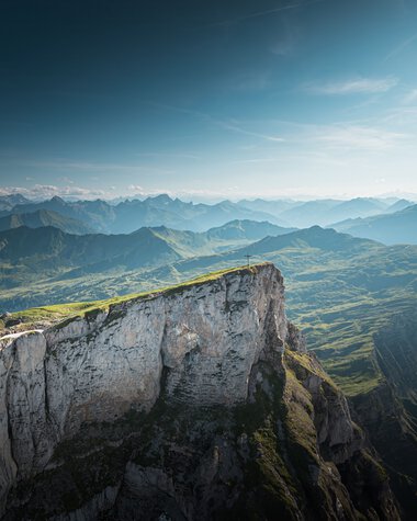 Berglandschaft mit grünen Hügeln und steilen Klippen unter einem blauen Himmel, aufgenommen vom Ifen.