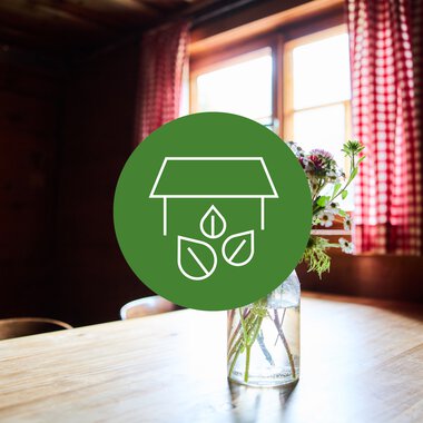 Innendekor mit Blumen in einem Glas auf einem Holztisch, natürliche Atmosphäre in einem gemütlichen Raum, Bio-Hotel