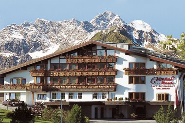 Das Hotel Almhof Rupp mit mehreren Balkonen und einer Bergkulisse im Hintergrund.