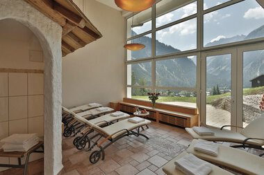 Innenraum eines Entspannungsbereichs mit Liegen, großen Fenstern und Bergblick, im Hotel »Alte Krone«.