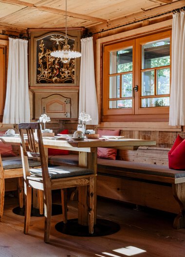 Gemütlicher Speiseraum im Gästehaus Fritz mit Holzmöbeln, großen Fenstern und natürlichem Licht. | © Gästehaus Fritz • Fotograf: Christina Hohner