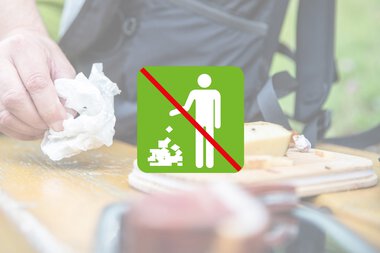 Verboten: Kein Müll auf den Boden werfen. Bild zeigt eine Hand, die Papier auf einen Tisch wirft, mit einem Symbol für kein Wegwerfen.