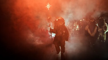 Krampus beim Adventszauber, inmitten von Rauch und Feuer, hält einen Stern in der Hand bei der Krampusjagd.