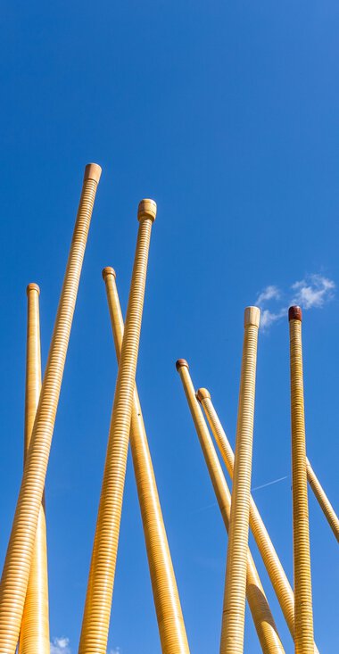 Wooden alphorn instruments being assembled outdoors against a blue sky during a festival. | © Kleinwalsertal Tourismus eGen • Photographer: Frank Drechsel