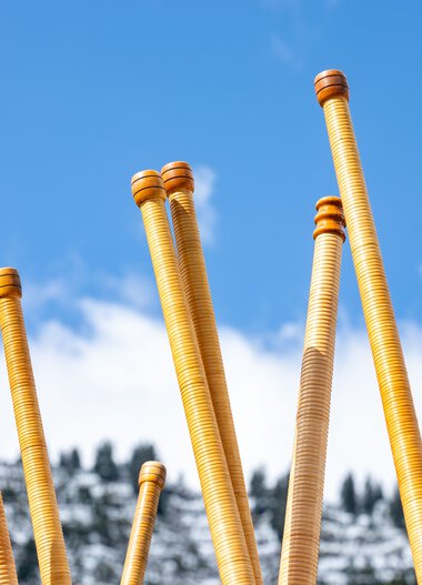 Mehrere Alphörner stecken in schneebedeckter Berglandschaft bei sonnigem Himmel auf dem Alphornfestival 2024.