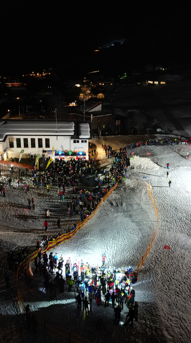 Abendliche Skispaß-Szene mit vielen Menschen auf den Pisten des Kleinwalsertals, beleuchtet bei Nacht.
