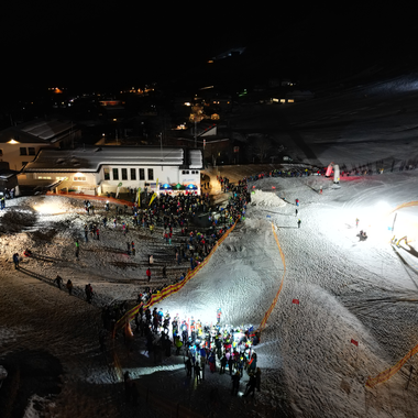 Abendliche Skispaß-Szene mit vielen Menschen auf den Pisten des Kleinwalsertals, beleuchtet bei Nacht.