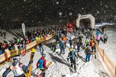 Skifahrer und Besucher bei der Bock uf Steil Veranstaltung im verschneiten Gelände mit Zelten und Einweihungsbogen.